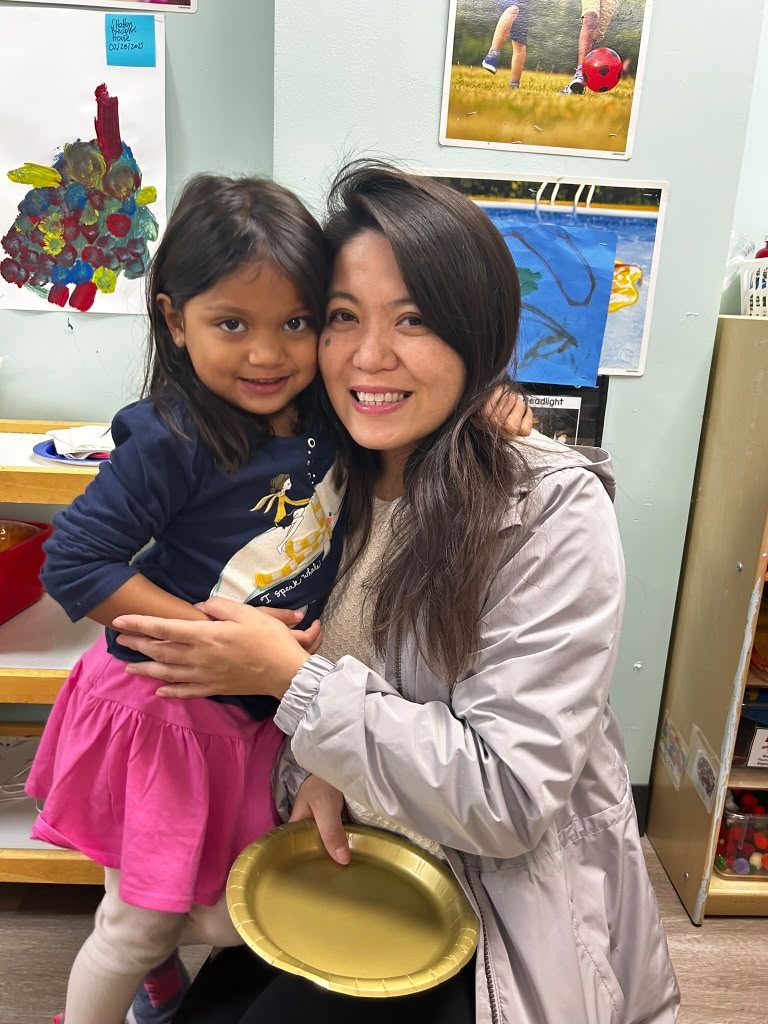 An ESPIN teacher holding a smiling child in a classroom.