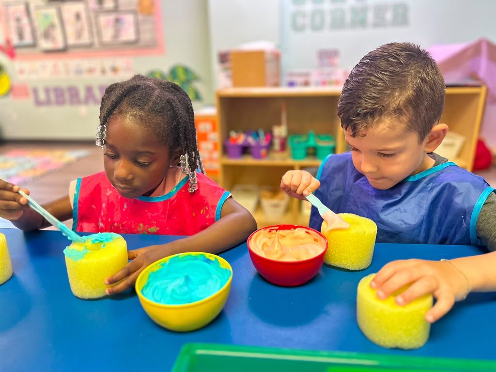 Two children scooping brightly coloured sensory material into bowls.