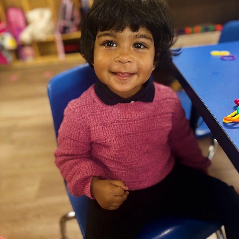 A child smiling at a classroom activity table.