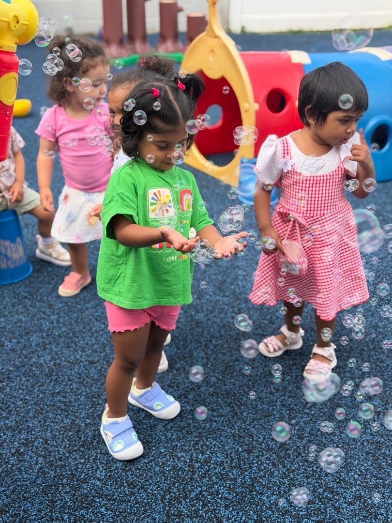 Children chasing soap bubbles together on the ESPIN playground.
