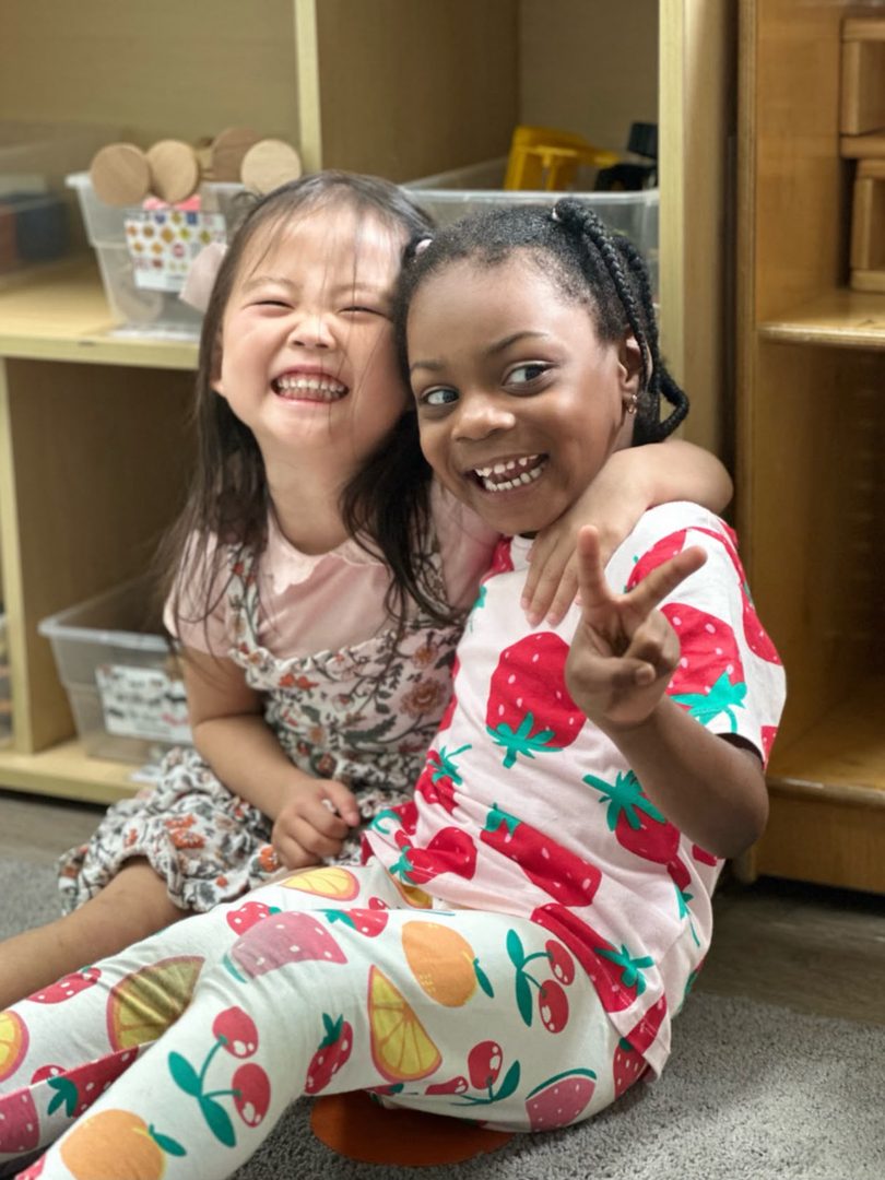 Two ESPIN children sitting together on the classroom floor, laughing.