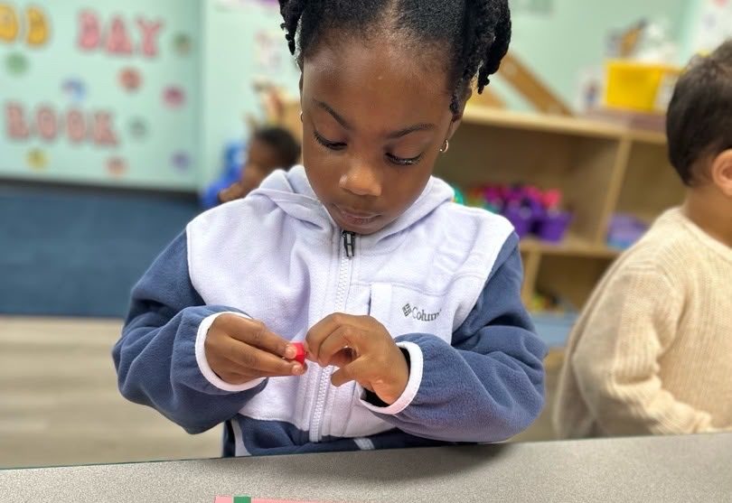 A Pre-K child working through a hands-on counting activity.